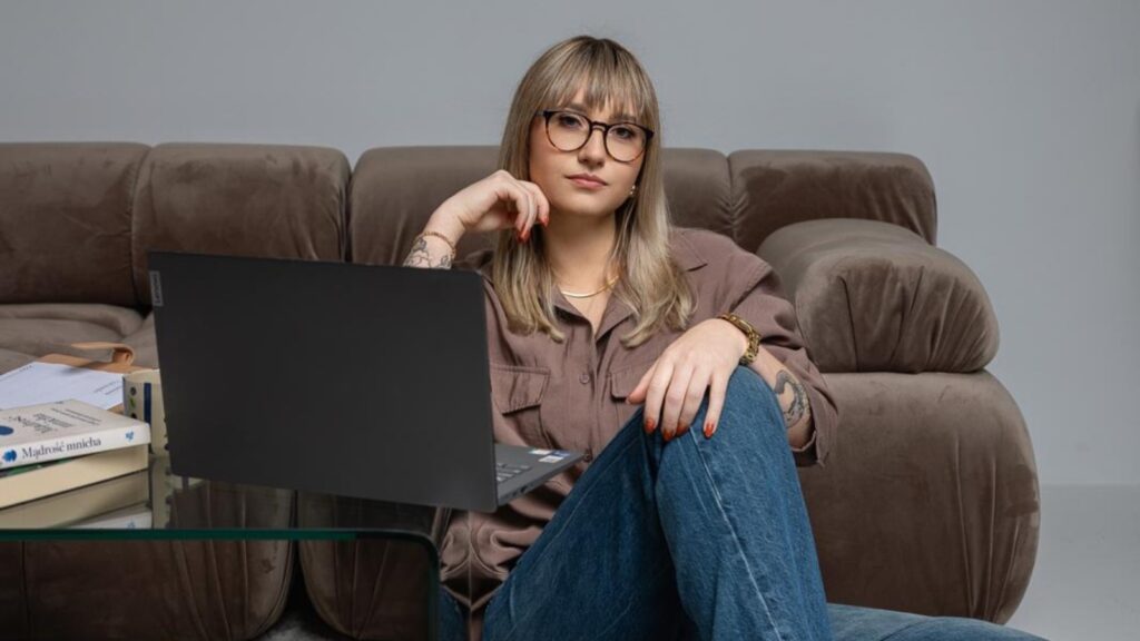 Patrycja Kania z laptopem, opierająca się o kanapę